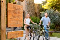 a man and a woman riding bikes next to a sign at Lares De Chacras in Chacras de Coria