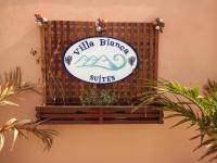 a sign on the side of a wall with plants at Villa Bianca Suítes in Beberibe