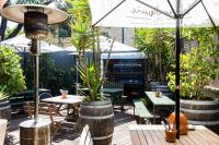 un patio al aire libre con mesas, sillas y una parrilla en The Erko Hotel, en Sídney