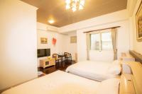 a bedroom with two beds and a tv and a table at Wenxin Homestay in Hualien City