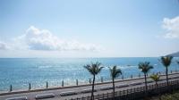 a road next to the ocean with palm trees at HL Sea Homestay in Hualien City