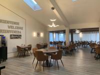a restaurant with tables and chairs and a chandelier at Hôtel Au Relais des Lilas in Parthenay