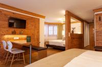 ein Schlafzimmer mit einem Bett und einem Schreibtisch mit einem Fernseher in der Unterkunft Hotel Jägerhof in Zermatt