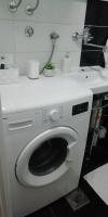 a white washing machine in a bathroom with a sink at Apartment M&amp;A in Osijek