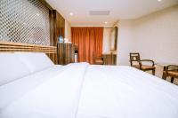 a large white bed in a room with chairs at Guide Hotel Taipei Xinyi in Taipei
