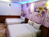 two beds in a hotel room with flowers on the wall at Hong Ben Hotel in Kenting
