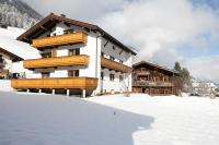 a building with wooden balconies in the snow at Appartement Zill in Tux