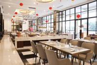 Un restaurante con mesas, sillas y ventanas. en Bigland Bogor Hotel Powered by Archipelago, en Bogor
