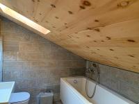 a bathroom with a white tub and a wooden ceiling at Hotelski in Verbier