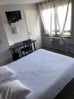 a bedroom with a large white bed and a desk at Logis Hôtel l&#39;Abricotine in Tain-lʼHermitage