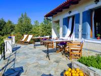una casa con patio con mesas y sillas en Helicon Muses Friendly Mountain B&amp;B Guesthouse, en Evangelístria