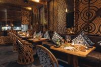 a restaurant with wooden tables and chairs in a room at Keemala in Kamala Beach