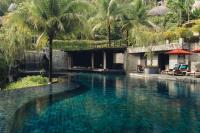 a swimming pool with blue water and palm trees at Keemala in Kamala Beach