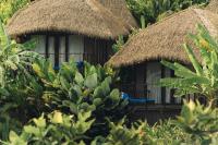two huts with straw roofs and a plant at Keemala in Kamala Beach