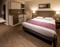 a hotel room with a large bed and a kitchen at Tulip Inn Thionville Residences in Thionville