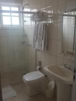a white bathroom with a toilet and a sink at Hotel Vila do Conde in Itu