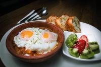 a bowl of food with eggs and strawberries on a plate at Hotel Miraflores in Ibarra