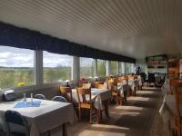 a dining room with tables and chairs and windows at Lufta Camping & Restaurang in Ånäset