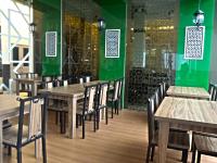 クアにあるHIG ホテルの木製のテーブルと椅子、緑の壁が備わるレストラン