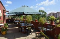 Un patio con mesas y sillas y una sombrilla. en Khweza Bed and Breakfast, en Nairobi