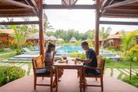 a man and woman sitting at a table in front of a pool at Island Lodge in Phu Quoc