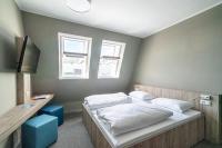 a bedroom with a bed with white sheets and two windows at WIROtel Warnemünde in Warnemünde
