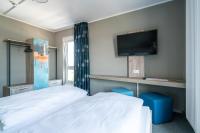 a bedroom with a bed and a flat screen tv at WIROtel Warnemünde in Warnemünde