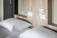 a bed with a white pillow and lights on the wall at WIROtel Warnemünde in Warnemünde