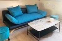 a blue couch with blue pillows and a table at Caudry : Appartement spacieux plein centre in Caudry