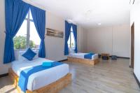 a bedroom with two beds and blue curtains at Paretto Seaview Hotel in Pantai Cenang