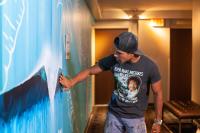 a man is painting a wall in a room at VIVE Hotel Waikiki in Honolulu