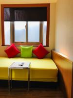 a room with a bench with colorful pillows and a table at Chiu Chunt Dint B&amp;B in Jiufen