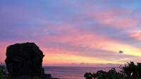 a sunset over the ocean with a rock in the foreground at Ming Jun Homestay in Eluan