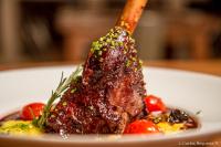 Un trozo de carne en un plato con salsa y tomates. en Best Western Patagonia, en Puerto Natales