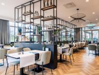 a restaurant with white tables and chairs and windows at Van der Valk Cuijk - Nijmegen in Nijmegen
