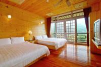 a bedroom with two beds and a television in a room with wooden walls at Kingtaiwan Hotel in Lugu Lake
