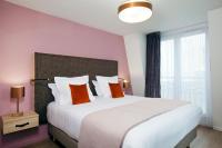 Un dormitorio con una gran cama blanca con almohadas naranjas. en Residhome Puteaux La défense, en Puteaux