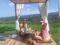 twee mensen aan een tafel op een dek bij Bali De Pardis Cottage in Munduk