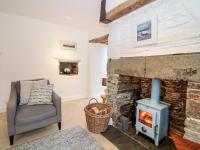 a living room with a stone fireplace and a chair at 1 Jubilee Cottage in Tintagel