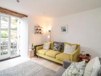 a living room with a yellow couch and a sliding glass door at 1 Jubilee Cottage in Tintagel