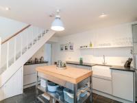 a kitchen with white cabinets and a wooden counter top at 1 Jubilee Cottage in Tintagel