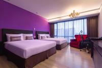 a purple room with two beds and a red chair at FX Hotel Taipei Nanjing East Road Branch in Taipei