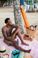 a man sitting on the beach next to a tree at VIVE Hotel Waikiki in Honolulu