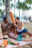 a man and woman sitting on a blanket on the beach at VIVE Hotel Waikiki in Honolulu