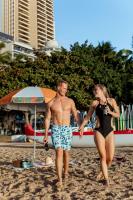 a man and a woman walking on the beach at VIVE Hotel Waikiki in Honolulu