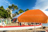 an orange umbrella and a boat on a beach at VIVE Hotel Waikiki in Honolulu