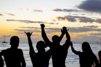 a group of people standing on the beach at sunset at VIVE Hotel Waikiki in Honolulu