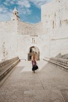 a woman is walking in front of a building at The Pucic Palace in Dubrovnik