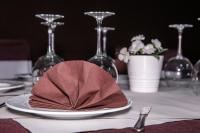 Hotel Ancora في فينيستيري: منديل على طبق على طاولة عليها كؤوس نبيذ