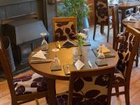 ein Holztisch mit Stühlen und ein Kamin in einem Restaurant in der Unterkunft The Hand Hotel Llangollen by Compass Hospitality in Llangollen